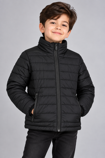 Young boy wearing black lightweight quilted puffer jacket front view with zip closure
