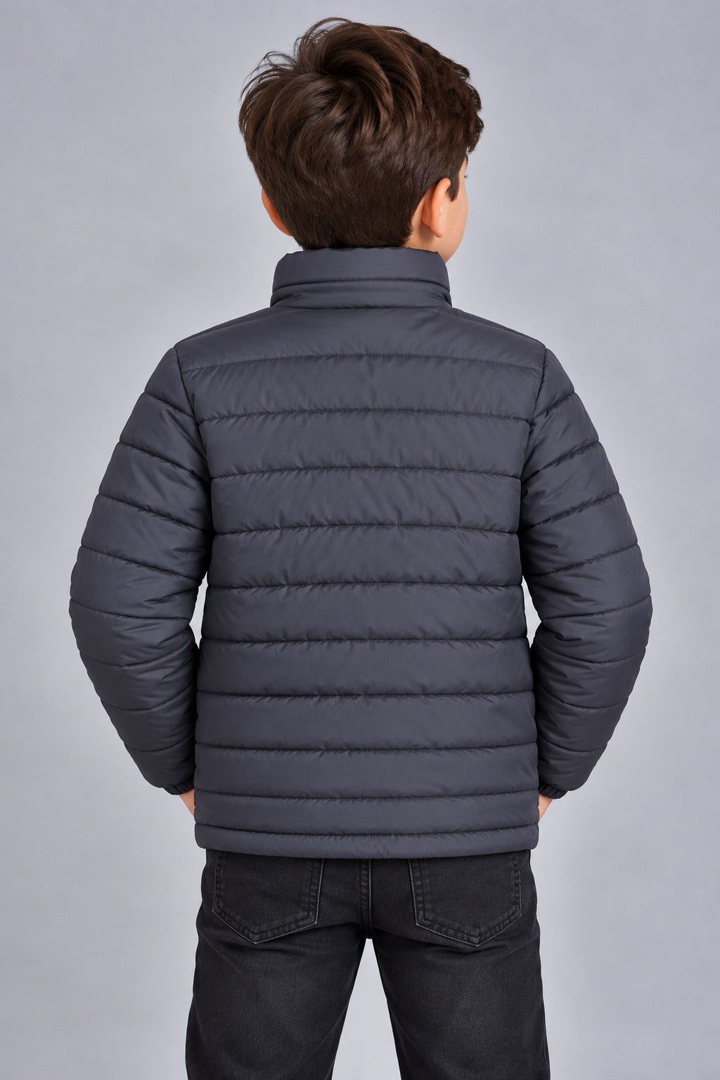 Young boy wearing charcoal grey lightweight quilted puffer jacket front view with zip closure