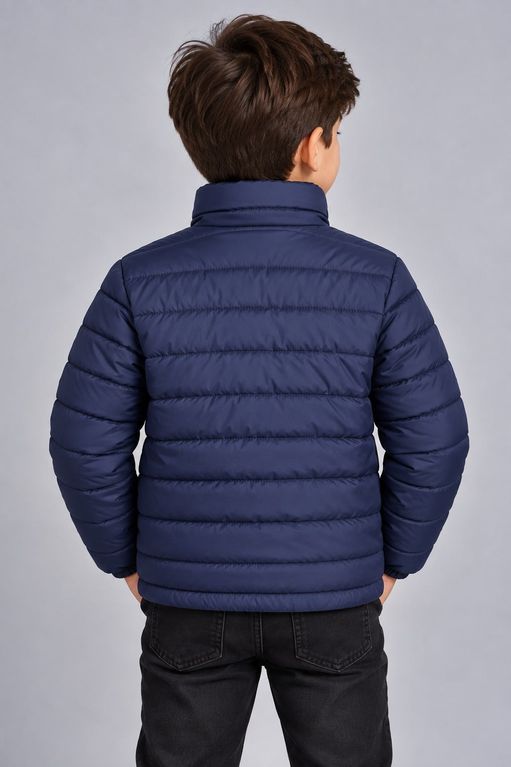 Young boy wearing navy blue lightweight quilted puffer jacket front view with zip closure