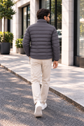 Man wearing charcoal grey horizontal quilted winter puffer jacket street style back view walking