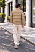 Man wearing khaki beige horizontal quilted winter puffer jacket street style back view walking