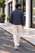 Man wearing navy blue horizontal quilted winter puffer jacket street style back view walking