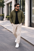 Man wearing olive green lightweight quilted puffer jacket street style front view walking outside